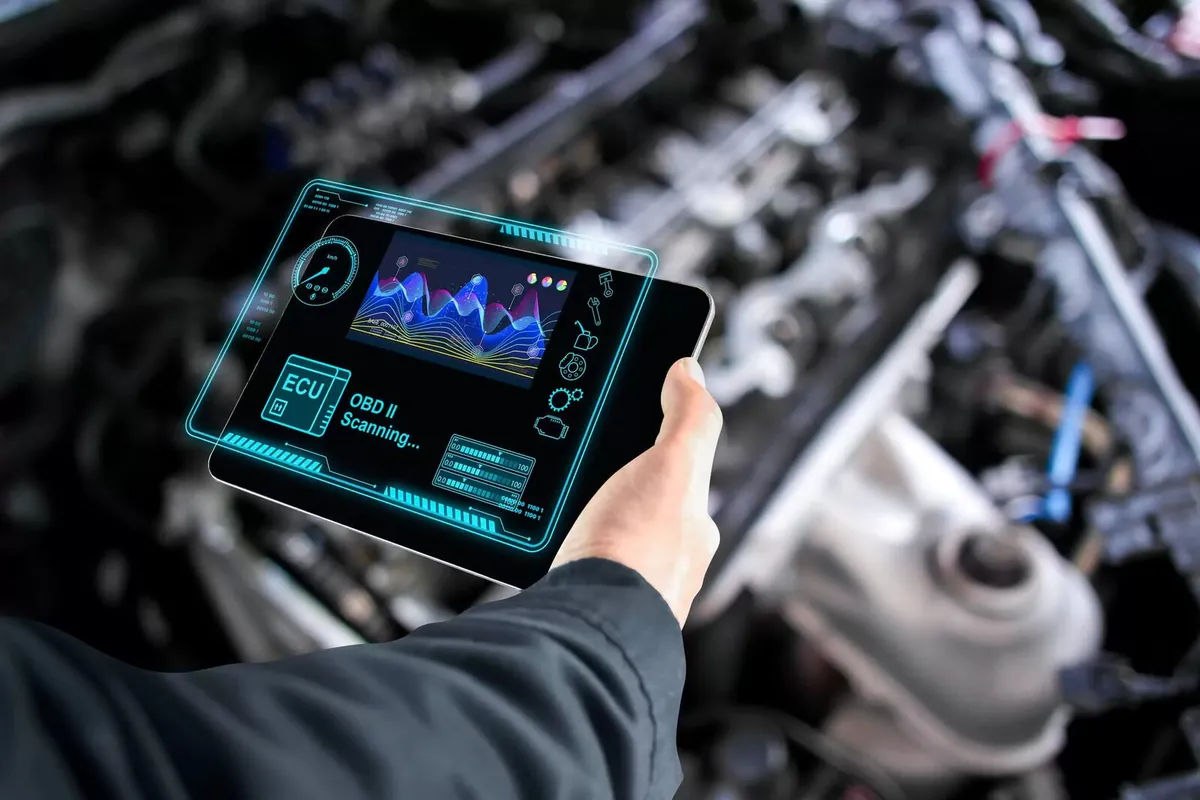 Une personne utilise une tablette de diagnostic près d’un moteur.